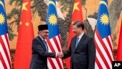 In this photo released by the Prime Minister's Office of Malaysia, Malaysia Prime Minister Anwar Ibrahim, left, shakes hands with Chinese President Xi Jinping during a meeting at the Great Hall of the People in Beijing.