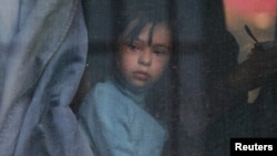Un niño mira por la ventana de un autobús mientras los civiles evacuados de la región ucraniana de Jersón, controlada por Rusia, llegan a una estación de tren local, en la ciudad de Dzhankoi, en Crimea, Ucrania, el 2 de noviembre de 2022.