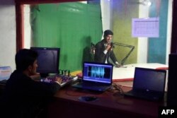 FILE - Afghan media personnel work inside a broadcast control room at Hamisha Bahar Local Radio station in Jalalabad, Dec. 11, 2021.