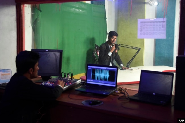 FILE - Afghan media personnel work inside a broadcast control room at Hamisha Bahar Local Radio station in Jalalabad, Dec. 11, 2021.