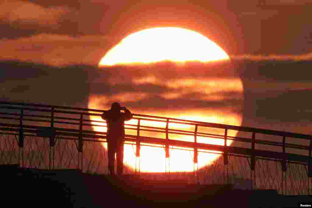 A man on a bridge takes a photograph of the first sunrise of the year at a park in Seoul, South Korea.