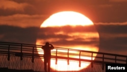 A man on a bridge takes a photograph of the first sunrise of the year at a park in Seoul, South Korea.