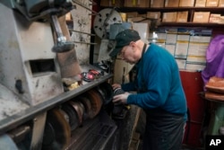 Jaira Cardenas, owner of Alpha Shoe Repair Corp., polishes a pair of boots he is repairing on February 3, 2023 in New York.