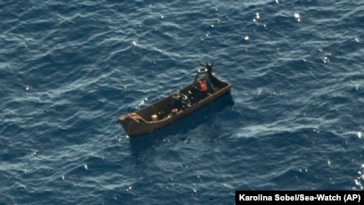 Four migrant survivors wave for help as they are in distress at sea, Aug. 8, 2023. Forty-one people are believed to be dead after a boat carrying migrants capsized off Tunisia in rough seas, the Italian Red Cross and rescue groups reported.