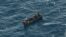 Four migrant survivors wave for help as they are in distress at sea, Aug. 8, 2023. Forty-one people are believed to be dead after a boat carrying migrants capsized off Tunisia in rough seas, the Italian Red Cross and rescue groups reported.