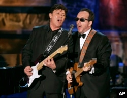 FILE - Robbie Robertson, left, and Elvis Costello play in an all-star tribute to New Orleans at the end of the Rock and Roll Hall of Fame induction ceremonies, March 13, 2006, in New York. Robertson died August 9, 2023, at age 80, his manager said.