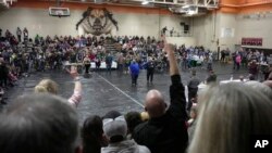 A man raises his hand with a question for East Palestine (Ohio) Mayor Trent Conaway, center, during a town hall meeting at East Palestine High School, Feb. 15, 2023. The meeting was held to answer questions about cleanup from a Feb. 3 train derailment.