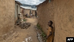 Congolese refugees walk in an alley way at the Kiziba Refugee Camp in Karongi, Rwanda, on March 27, 2024. The camp hosts over 15,000 refugees, mainly Congolese who flee instability in the eastern Democratic Republic of Congo. 