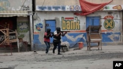 FILE: Police officers take cover during an anti-gang operation in Port-au-Prince, Haiti, Tuesday, April 25, 2023, a day after a mob in the Haitian capital pulled 13 suspected gang members from police custody and burned them to death with gasoline-soaked tires. 