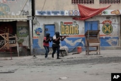 Petugas polisi berlindung selama operasi anti-geng di lingkungan Portail Port-au-Prince, Haiti, Selasa, 25 April 2023 (Foto: AP)