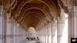 A man at the BAPS Swaminarayan Akshardham checks his phone inside the garland-like path, or parikrama, which serves as an ornate covered walkway to the largest Hindu temple outside India in the modern era, Oct. 4, 2023, in Robbinsville, NJ.