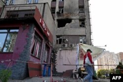 A resident walks past a partially destroyed residential building in Kyiv after a Russian drone strike, May 28, 2023.