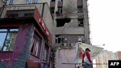 A resident walks past a partially destroyed residential building in Kyiv after a Russian drone strike, May 28, 2023. 