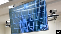 Alexei Liptser, left, and Vadim Kobzev, lawyers for Alexey Navalny, are seen on a video link provided by the Russian Federal Penitentiary Service during a session in Moscow City Court, in Moscow, Russia, Aug. 20, 2024. 