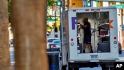 A FedEx employee works inside his truck during extreme heat, in Las Vegas, Nevada, Aug. 25, 2023.