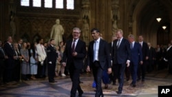 Perdana Menteri Sir Keir Starmer (kiri) dan pemimpin Konservatif Rishi Sunak (kanan) memimpin anggota parlemen melalui Lobi Pusat di Istana Westminster menjelang Pembukaan Parlemen Negara di London, Rabu, 17 Juli 2024. (Dan Kitwood/POOL via AP)