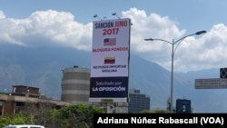 Mensajes que denuncian los efectos de las sanciones impuestas por EEUU contra Venezuela se ven en vallas en la principal autopista de la capital venezolana.