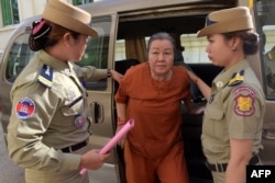 FILE - Lim Mony (C), a Cambodian senior officer from the local rights group The Cambodian Human Rights and Development Association (ADHOC), is escorted by police officials outside the appeals court in Phnom Penh on August 30, 2016.