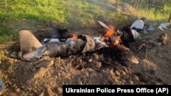 In this photo provided by the Ukrainian Police Press Office, fragments of a Russian rocket shot down by Ukraine's air defense system smolder after a night rocket attack in the Kyiv region, Ukraine, May 18, 2023. (Ukrainian Police Press Office via AP)