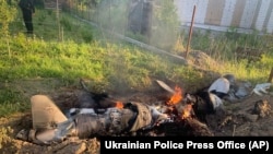 In this photo provided by the Ukrainian Police Press Office, fragments of a Russian rocket shot down by Ukraine's air defense system smolder after a night rocket attack in the Kyiv region, Ukraine, May 18, 2023. (Ukrainian Police Press Office via AP)