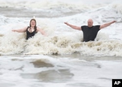 Jeremy Reddout y su hija, Elexus, disfrutan de las olas entre Murdoch's y Pleasure Pier mientras llueve en Galveston, Texas, el 19 de junio de 2024.