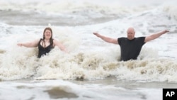 Jeremy Reddout and his daughter, Elexus, enjoy the waves between Murdoch's and Pleasure Pier as rain falls in Galveston, Texas, June 19, 2024.