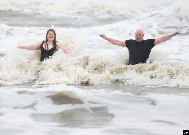 Jeremy Reddout y su hija, Elexus, disfrutan de las olas entre Murdoch's y Pleasure Pier mientras llueve en Galveston, Texas, el 19 de junio de 2024.