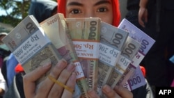 Seorang perempuan memperlihatkan uang yang akan dibagikan kepada para kerabat untuk Idul Fitri di Malang, Jawa Timur, 15 Juni 2016. (Foto: Aman Rochman/AFP/ilustrasi)