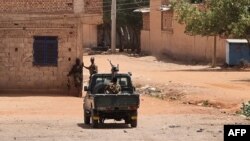 Sudanese army soldiers rest next to a building in Khartoum on May 25, 2023. Fighting eased in Sudan, the second full day of a ceasefire that has allowed beleaguered civilians to venture out, even as they await safe aid corridors and escape routes. 