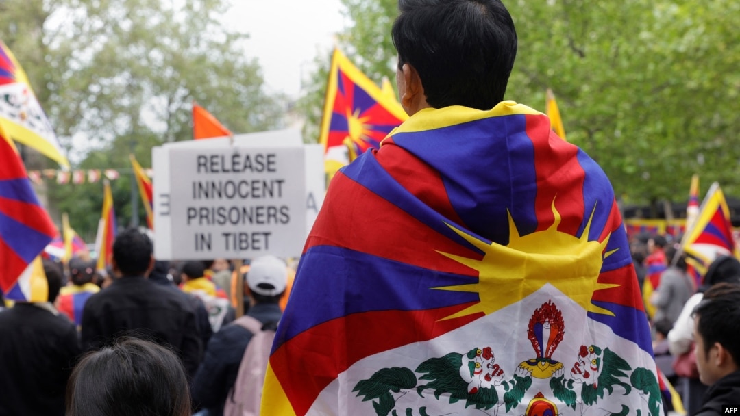FILE - Protesters wearing Tibetan flags on their shoulders take part in a demonstration in support of members of the Tibetan and Uyghur community and against the Chinese President's two-day state visit to France, at Place de la Republique in Paris, May 5, 2024. 