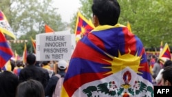 FILE - Protesters wearing Tibetan flags on their shoulders take part in a demonstration in support of members of the Tibetan and Uyghur community and against the Chinese President's two-day state visit to France, at Place de la Republique in Paris, May 5, 2024. 