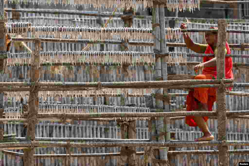 A woman hangs fish to dry on a hot day in Mumbai, India.