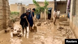 Warga tampak membersihkan lumpur dari halaman rumah mereka setelah banjir melanda wilayah Maymana, ibu kota dari provinsi Faryab di Afghanistan, pada 19 Mei 2024. (Foto: Reuters/Stringer)