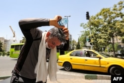 A man pours water on his head from a bottle to cool off during a heat wave in Tehran on July 11, 2023. (Photo by ATTA KENARE / AFP)