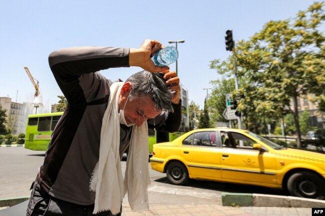 A man pours water on his head from a bottle to cool off during a heat wave in Tehran on July 11, 2023. (Photo by ATTA KENARE / AFP)