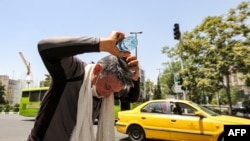 Čovjek se rashlađuje flašicom vode na ulici u Teheranu, glavnom gradu Irana. (Foto: AFP/ATTA KENARE)