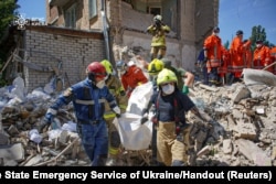 Rescuers carry the body of a person found under debris at the site where an apartment building was hit by a Russian missile strike in Kyiv, Ukraine, July 9, 2024.