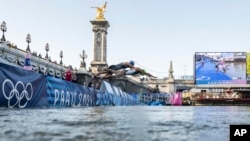 FILE - Athletes jump into the water to compete in the swimming race in the Seine river, during the mixed relay triathlon, at the 2024 Olympic Games, in Paris, France, Aug. 5, 2024.