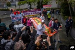 FILE - Protesters walk within a cordon line wearing number tags during a rally in Hong Kong, March 26, 2023.