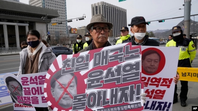 Manifestantes se reúnen para oponerse a la visita del presidente de Corea del Sur, Yoon Suk Yeol, a Japón, frente a la embajada de Estados Unidos en Seúl, el 16 de marzo de 2023. Los letreros dicen "Un traidor projaponés".