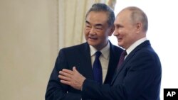 Presiden Rusia Vladimir Putin (kanan) dan Menteri Luar Negeri China Wang Yi berjabat tangan sebelum pertemuan di Istana Konstantin di St. Petersburg, Rusia, Rabu, 20 September 2023. (Mikhail Metzel, Sputnik, Kremlin Pool Photo via AP)