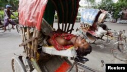 বাংলাদেশের ঢাকায় প্রচণ্ড গরমে অতিষ্ঠ জীবন। এতে জনজীবনে নেমে এসেছে চরম অস্বস্তি।গরমের কারণে ঠিকমতো রিকশাও চালানো যাচ্ছে না। তাই ভাড়া টানার পর কিছু সময় জিরিয়ে নিচ্ছে একজন রিকশা চালক। (ফাইল ছবি) 