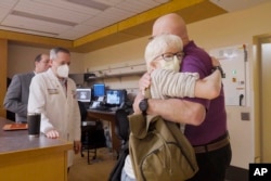 In this photo provided by Washington University, Jeff Backus hugs his wife after an experimental radiation procedure for his irregular heartbeat in St. Louis on Tuesday, Feb. 14, 2023. (Huy Mach/Washington University, St. Louis via AP)