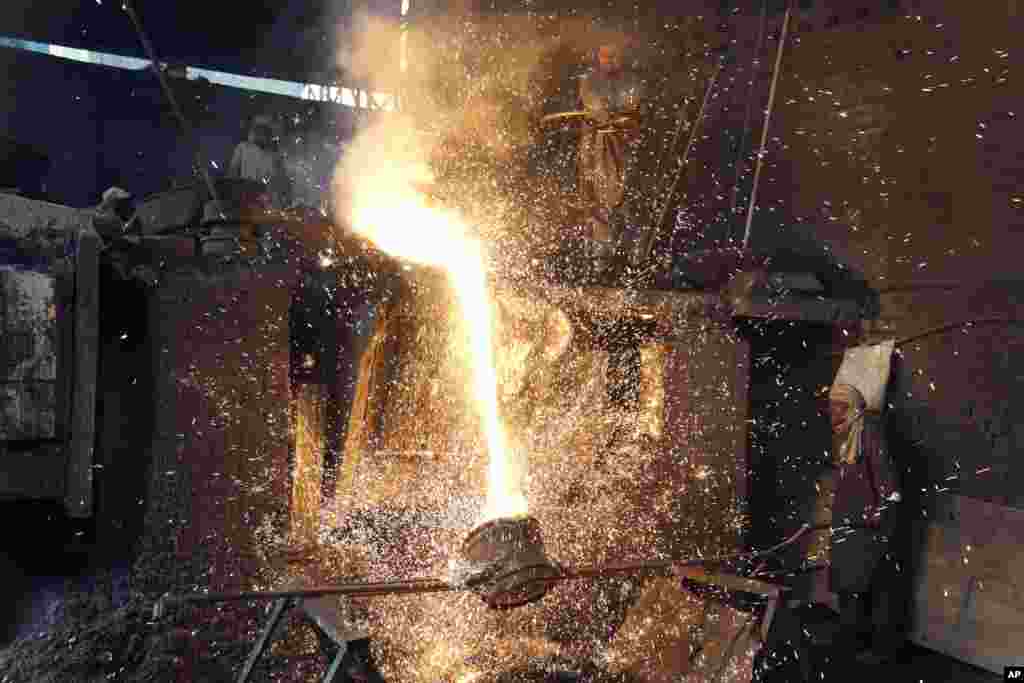 Laborers pour molten metal in a steel factory in Lahore, Pakistan, April 29, 2023.