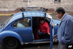 Taxi rank manager Rafael Ortega helps passengers into a Volkswagen Beetle in the Cuautepec neighborhood of Mexico City, Friday, June 21, 2024. (AP Photo/Aurea Del Rosario)