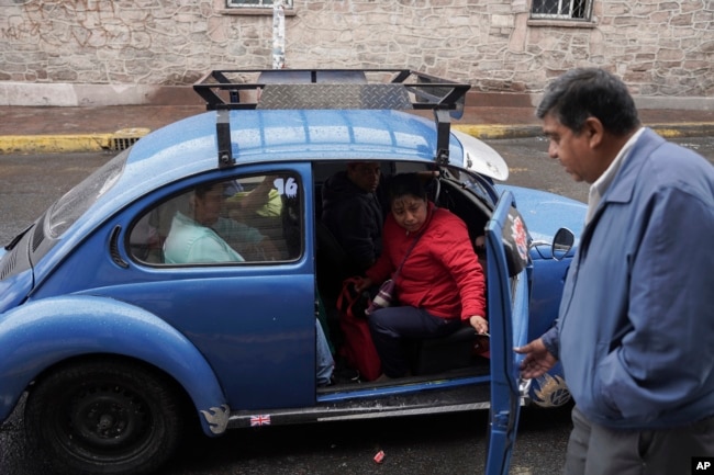 Taxi rank manager Rafael Ortega helps passengers into a Volkswagen Beetle in the Cuautepec neighborhood of Mexico City, Friday, June 21, 2024. (AP Photo/Aurea Del Rosario)