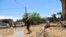 People stand in muddy water after heavy flooding in Baghlan province, in northern Afghanistan, May 12, 2024. Victims of the devastating floods are burying the dead and looking for the loved ones still missing. 