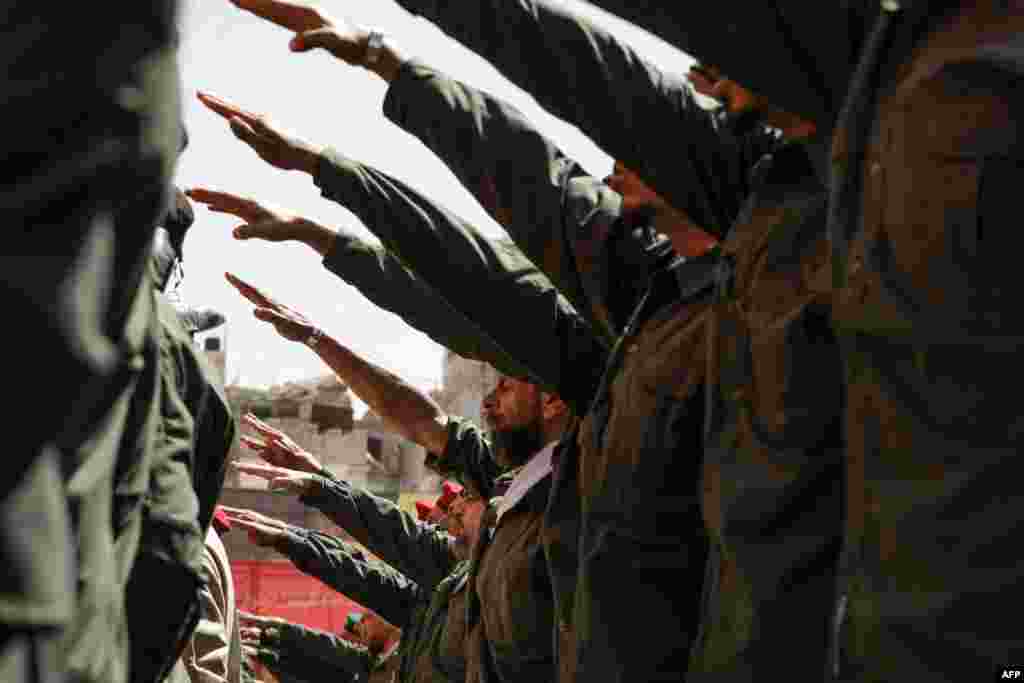 Palestinian members of a pro-Syrian government squad raise their arms in salute as they take part in a military parade to mark the annual Quds (Jerusalem) Day commemorations, in the Yarmouk refugee camp in Damascus, Syria. (Photo by LOUAI BESHARA / AFP)