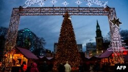 A Christmas tree greets visitors at the entrance to a traditional Christmas market in Berlin, Germany, Dec. 22, 2023, as the Marienkirche church (R) is seen in the background. 