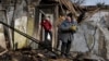 A woman holds food items found as she stands outside her house which was destroyed by a Russian drone attack in a residential neighborhood, in Zaporizhzhia, Ukraine, on March 28, 2024.